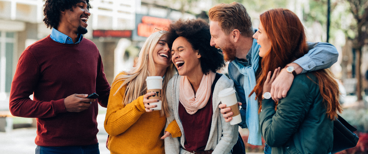 Header | Friends drinking coffee laughing on street